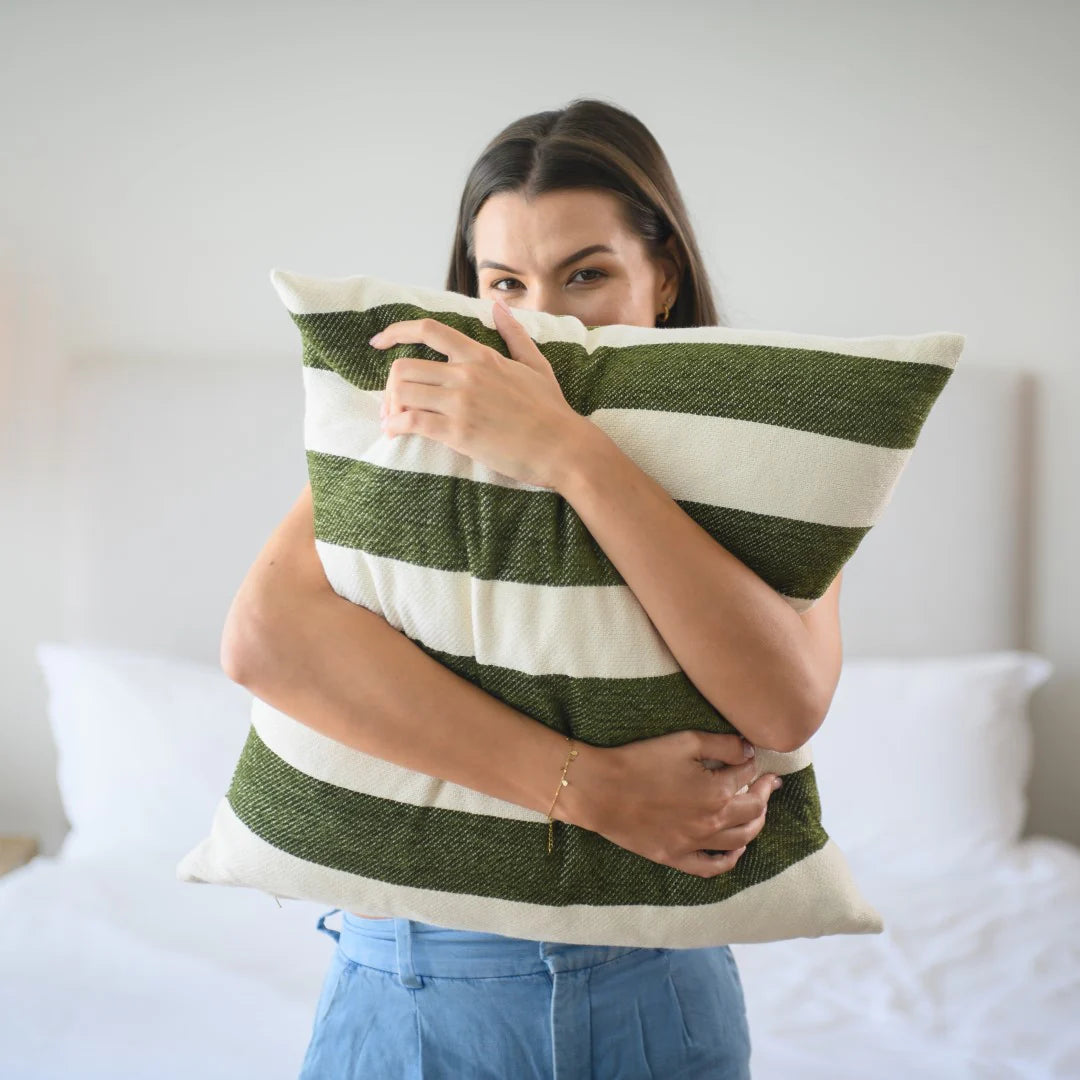 Woman holding a Protea Chenille Scatter Cushion in Hunter and Natural scatter pillow against a neutral background